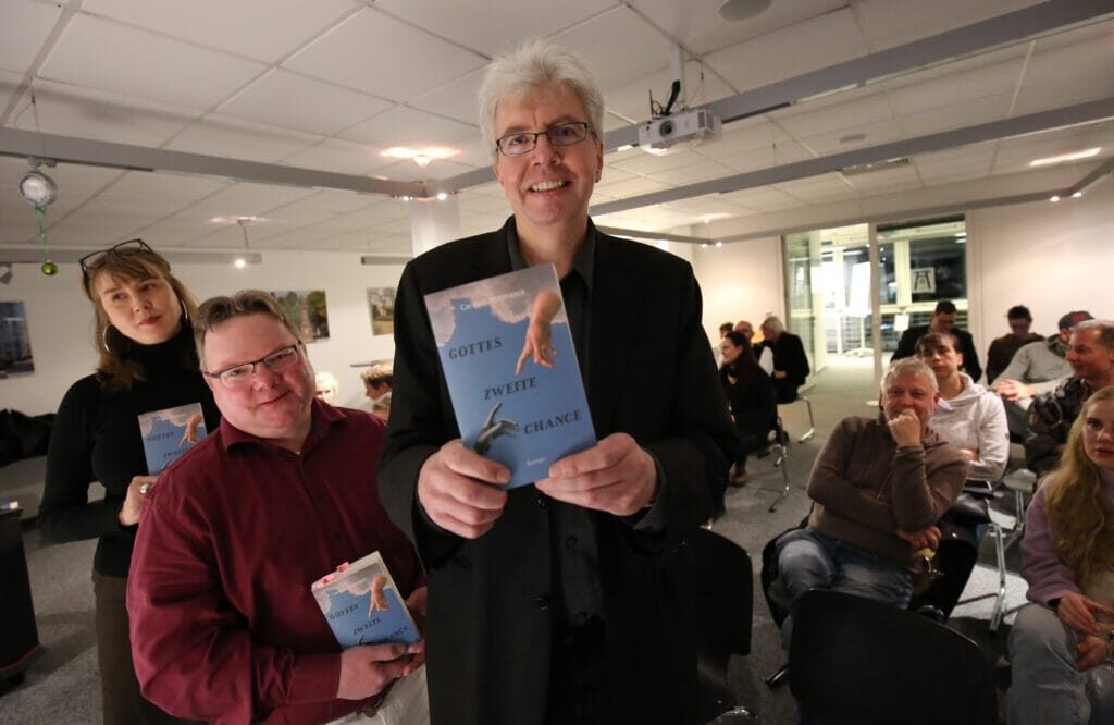 Carsten Wittmaack und seine Helfer posieren mit „Gottes zweiter Chance“ in der Hand bei der ersten Lesung